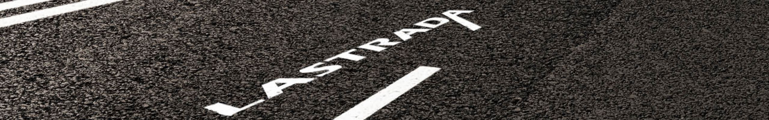 Straßenansicht mit aufgemaltem LASTRADA Schriftzug auf Asphalt.